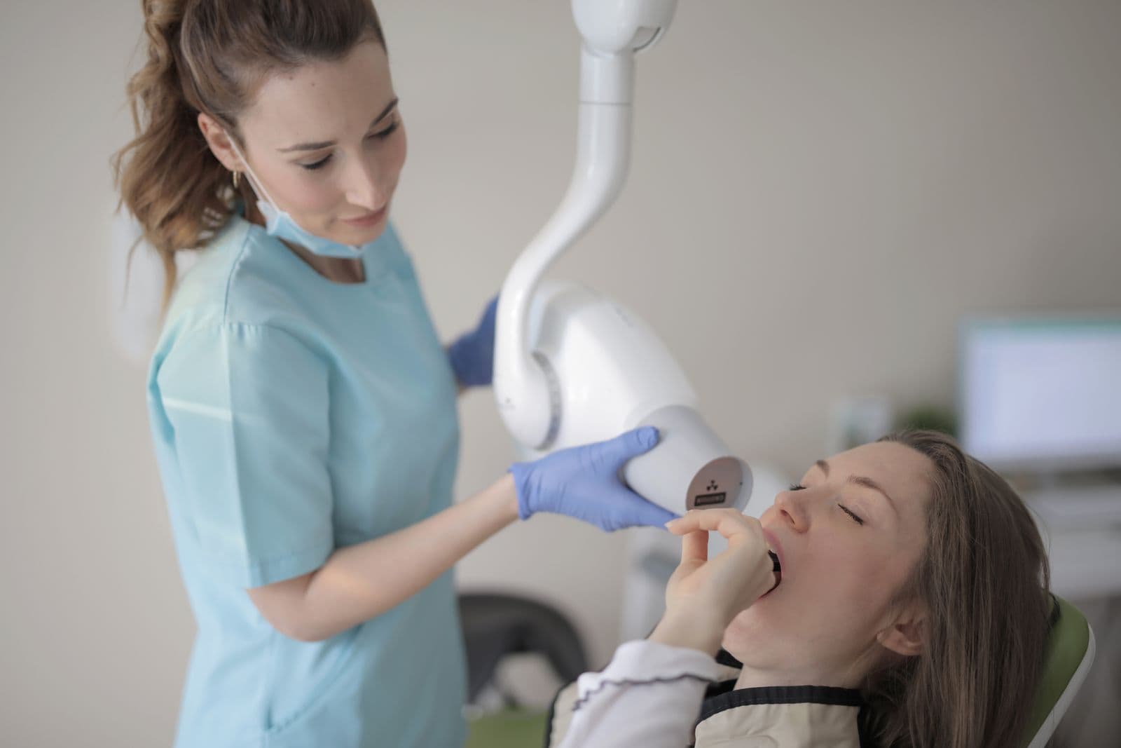 Modern klinikte diş hekimi hastaya röntgen cihazıyla muayene yapıyor